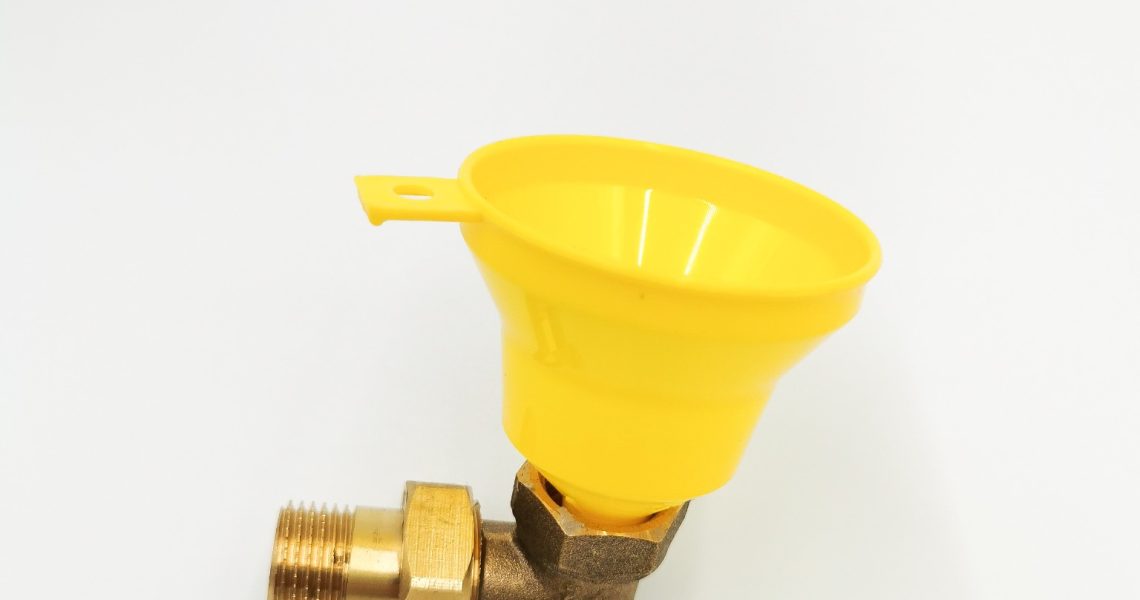 Żółty plastikowy lejek do wlewania uszczelniacza MultiSeal, zamocowany na mosiężnym kolanku z gwintem zewnętrznym – widok boczny na białym tle.